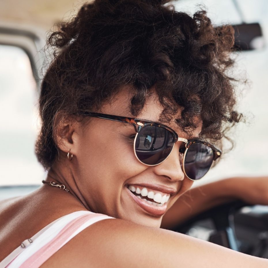 Frau mit Sonnenbrille, blickt über die Schulter.